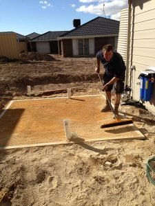Guy raking the base for a new rainwater tank