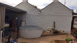 White base for rainwater tank on side of cottage in Kapunda SA