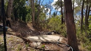 concrete pad on hill surrounded with trees ready for rainwater tank placement